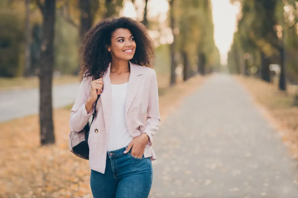 Woman walking on an autumn road wearing a pink blazer